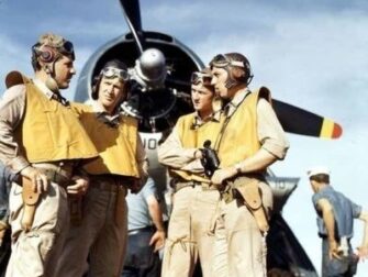 Vier bemanningsleden in uniform bij een historisch vliegtuig